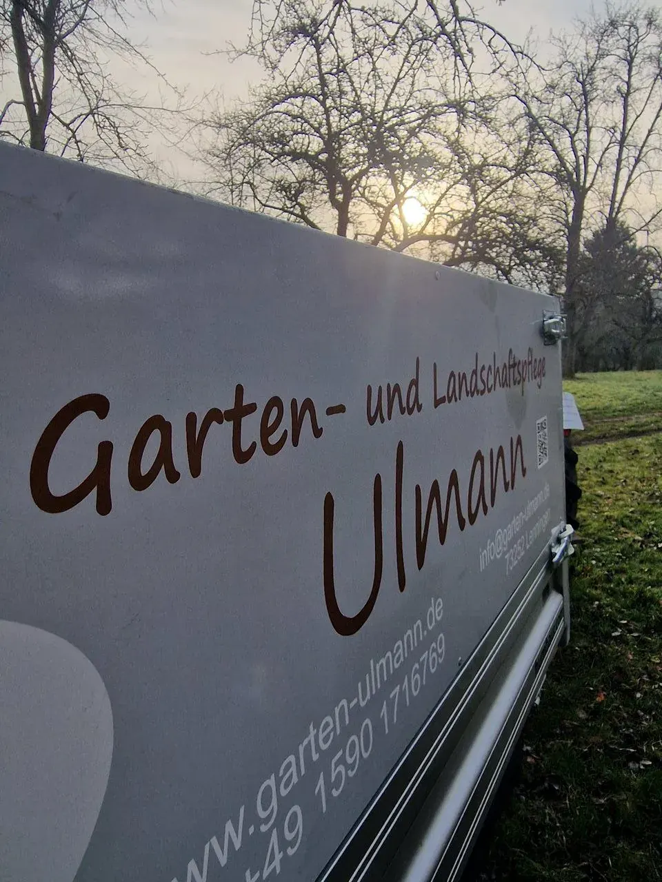 Ulmann-Anhänger mit Logo bei Sonnenaufgang auf einer Wiese